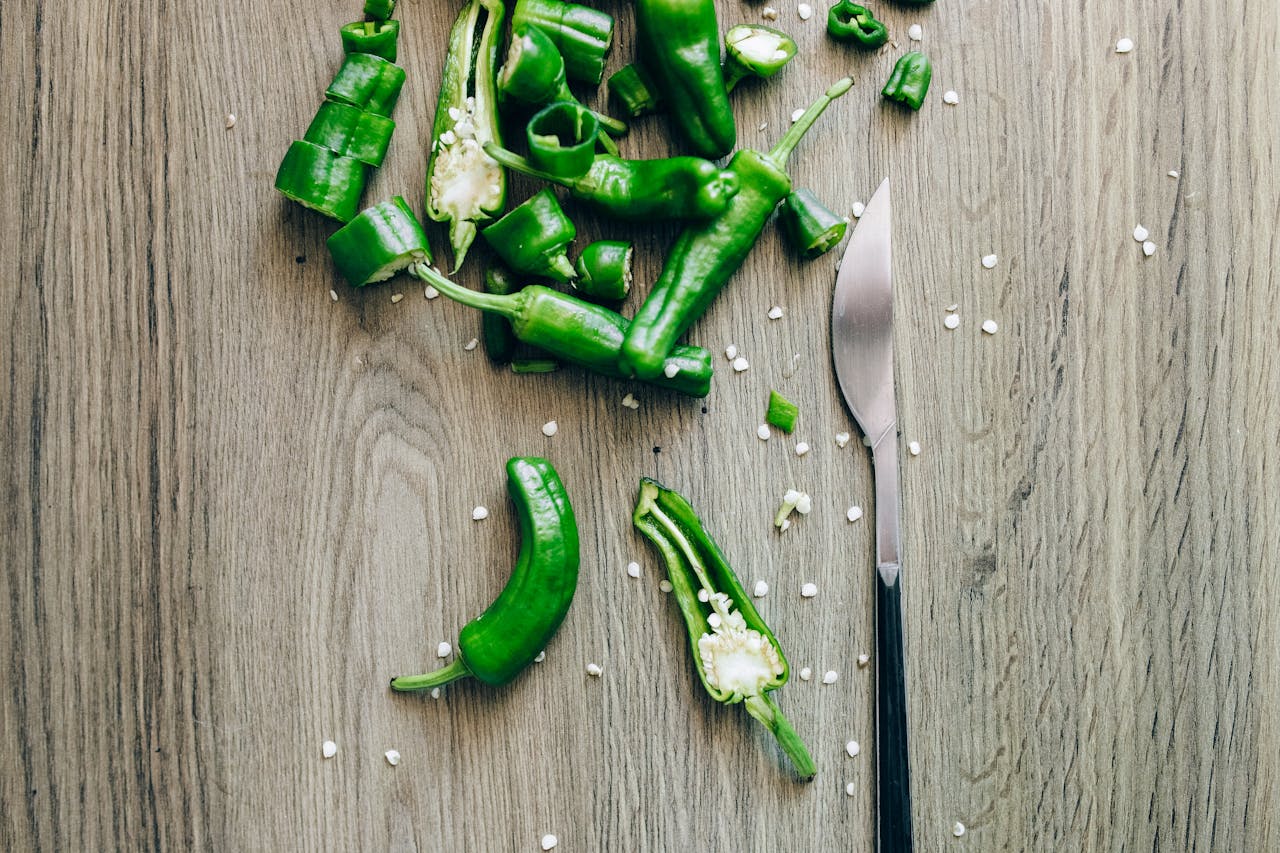 Sliced green chili peppers with seeds on a wooden surface, perfect for culinary themes.